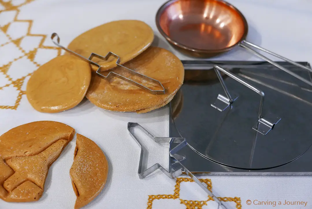 Ppopgi sitting on a yellow and white table cloth. The cookies are sitting with the molds.