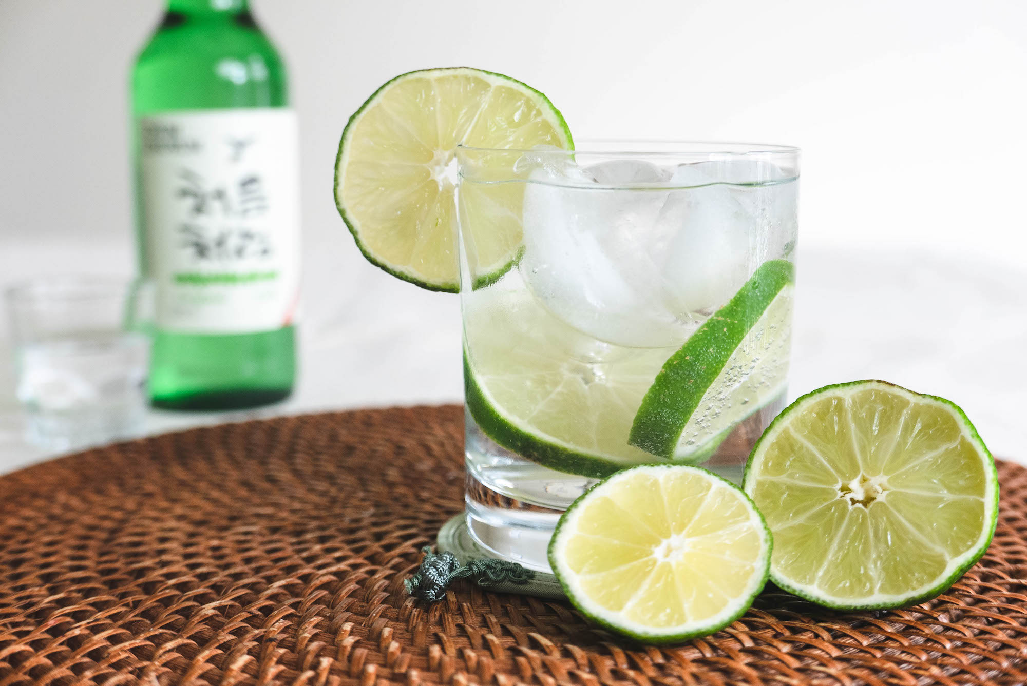 A glass of soju and tonic with slices of lime.