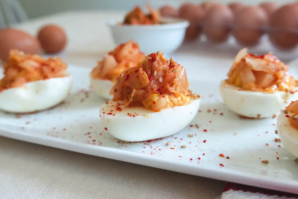 A side shot of kimchi topped deviled eggs.