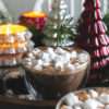 Bourbon hot chocolate drink next to Christmas tree candles and greenery