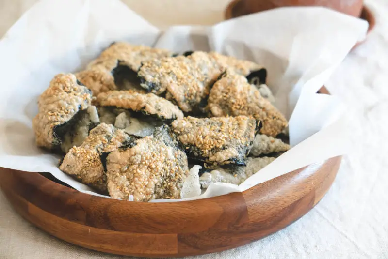 A wooden platter filled with Korean fried seaweed snacks.