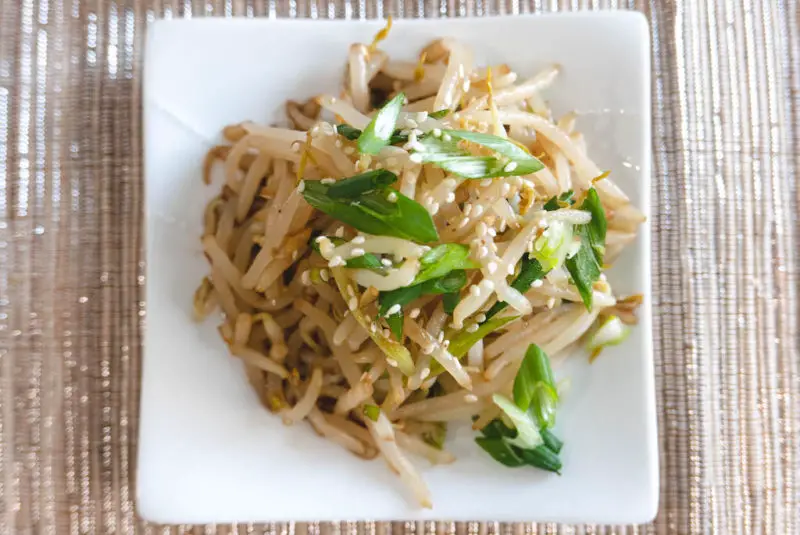 An overhead shot of sukju-namul muchim. The salad is made up of sprouts, green onions, and sesame seeds.