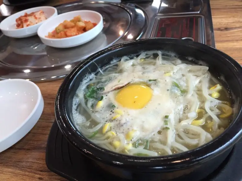 Soybean sprout soup in a black bowl.
