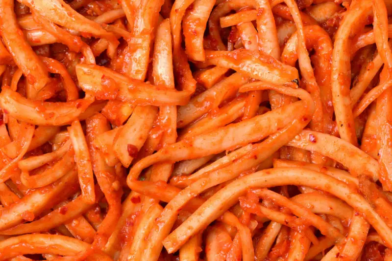 An overhead shot of seasoned bellflower root (doraji). It is bright red from the Korean seasoning.