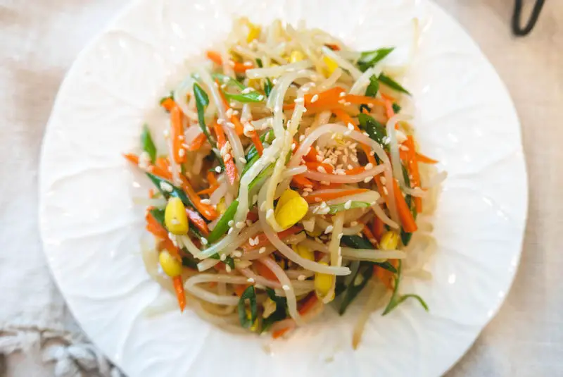An overhead shot of Korean soybean sprout salad. This salad contains carrots, green onions, sesame seeds, and soybean sprouts.