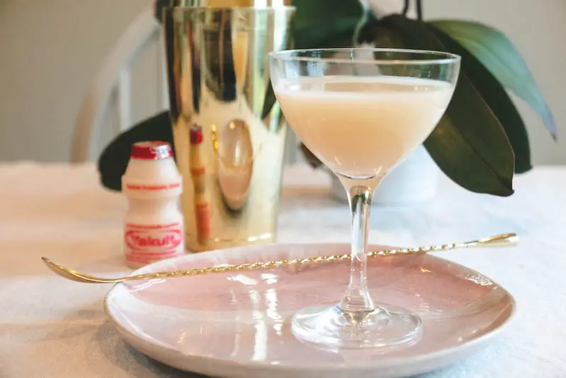 A side shot of the yakult soju cocktail, a bottle of Yakult, and a shaker. 