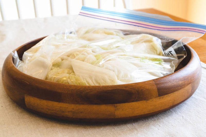 A side shot of cabbage in a Ziplock bag inside a wooden bowl. 
