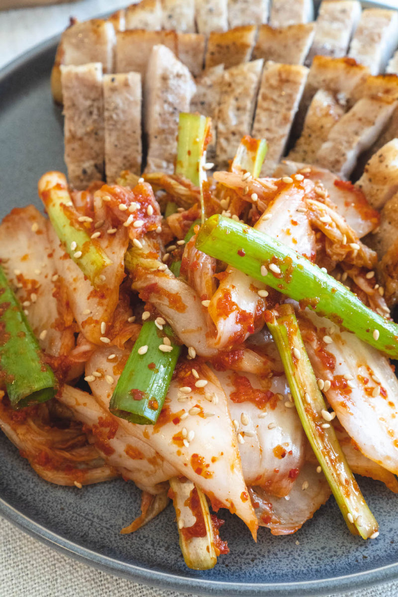 A side shot of fresh kimchi. The fresh kimchi sits next to grilled pork belly. 