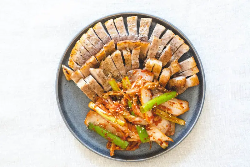 An overhead shot of fresh kimchi next to pork belly.