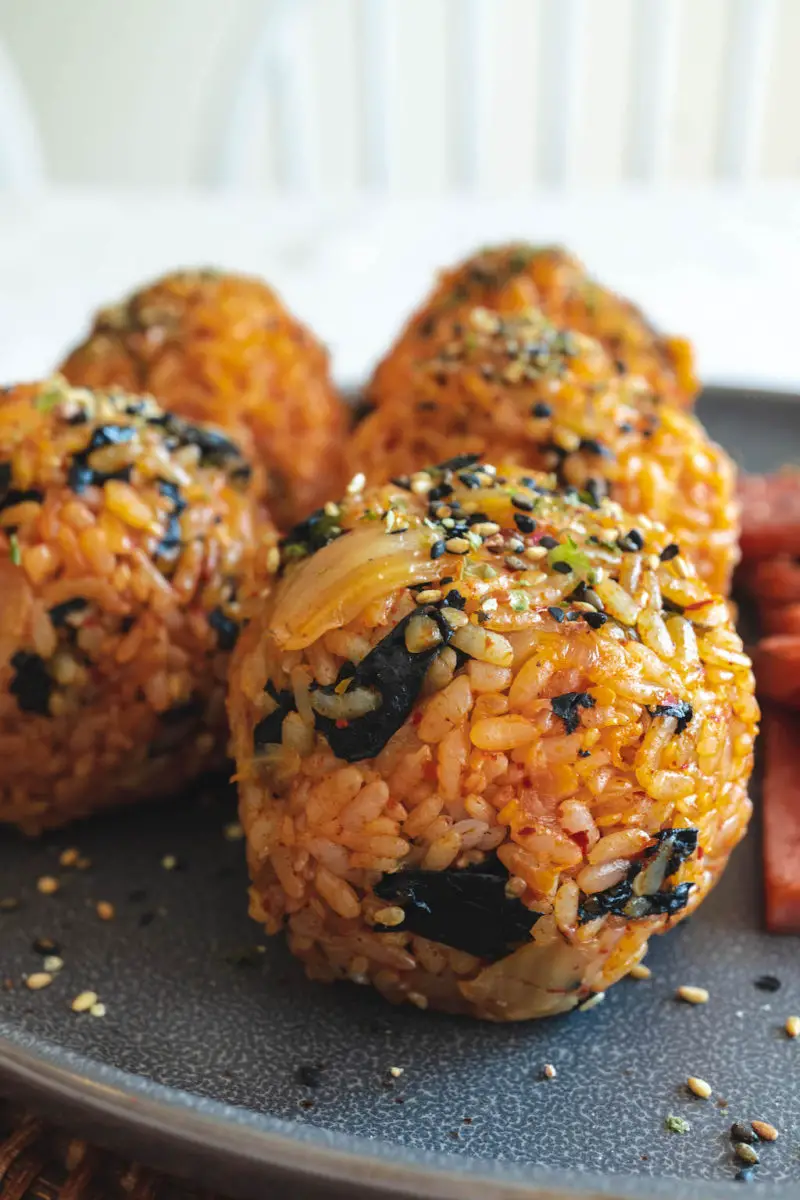 A side shot of 5 kimchi rice balls on a gray plate. 