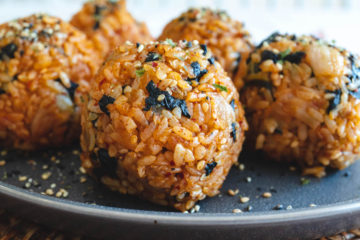A side shot of kimchi rice balls on a grey plate.