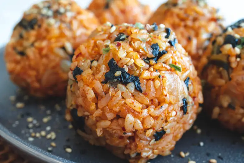 A closeup shot of multiple kimchi rice balls on a gray plate. 