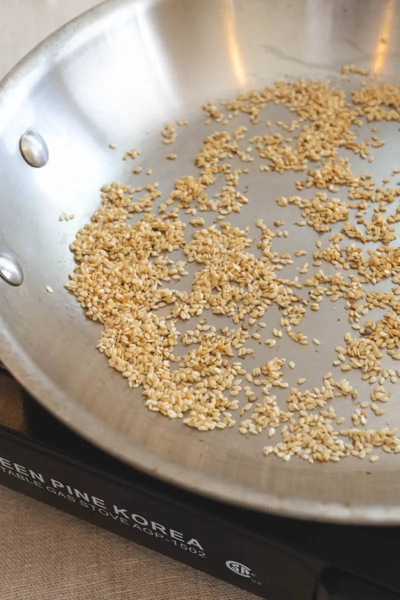 A side shot of toasted sesame seeds in a pan. The photo shoes you how to toast sesame seeds.