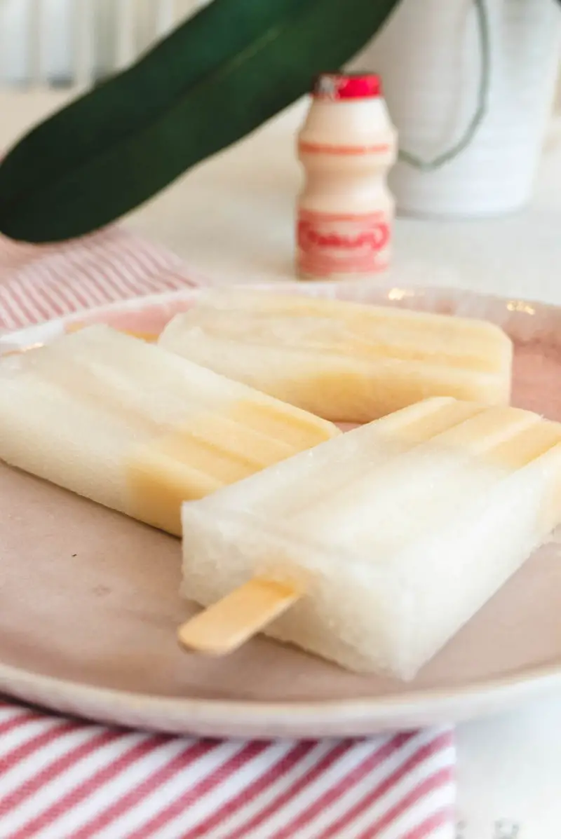 A side shot of Yakult soju popsicles on a pink plate.