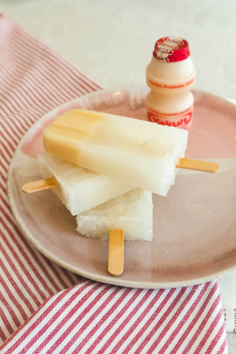 A side shot of popsicles stacked on a pink plate.