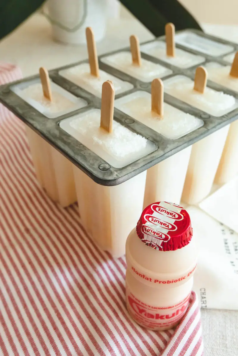 A side shot of Yakult next to the mold filled with popsicles. 