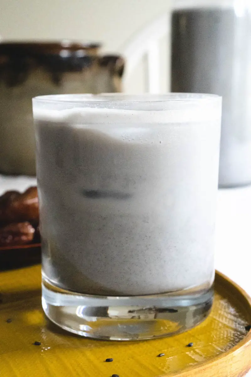 A close up side shot of black sesame milk on a yellow tray.