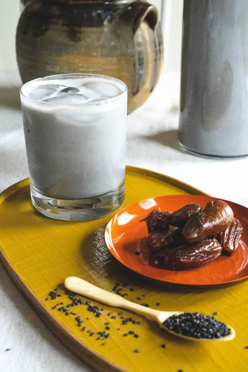 The light grey milk sitting on a yellow tray next to a bowl of dates. 