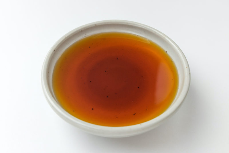 An overhead shot of light brown Korean fish sauce in a white bowl. 