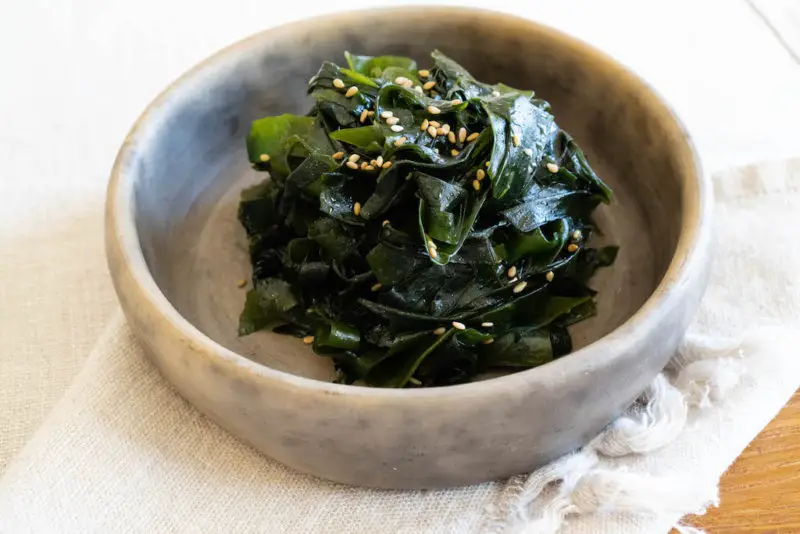 A side shot of miyeok namul in a stone bowl.