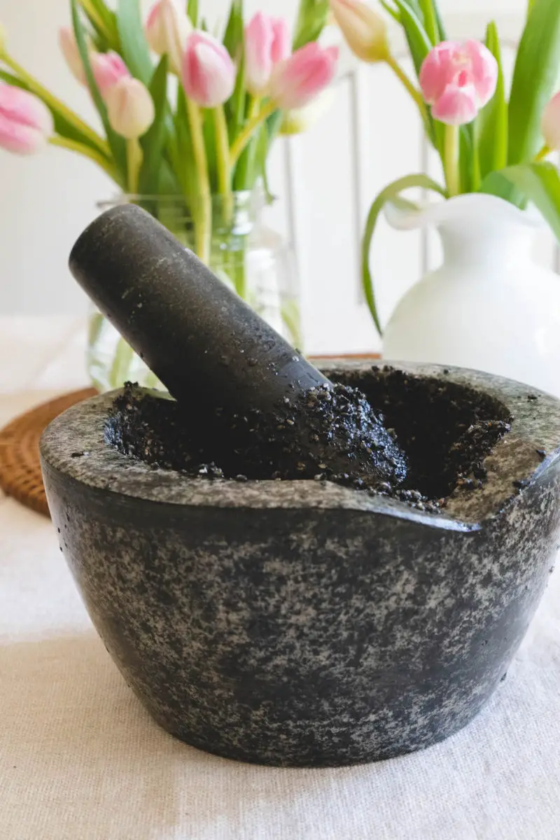 A Morter and pestle filled with black sesame seeds. 