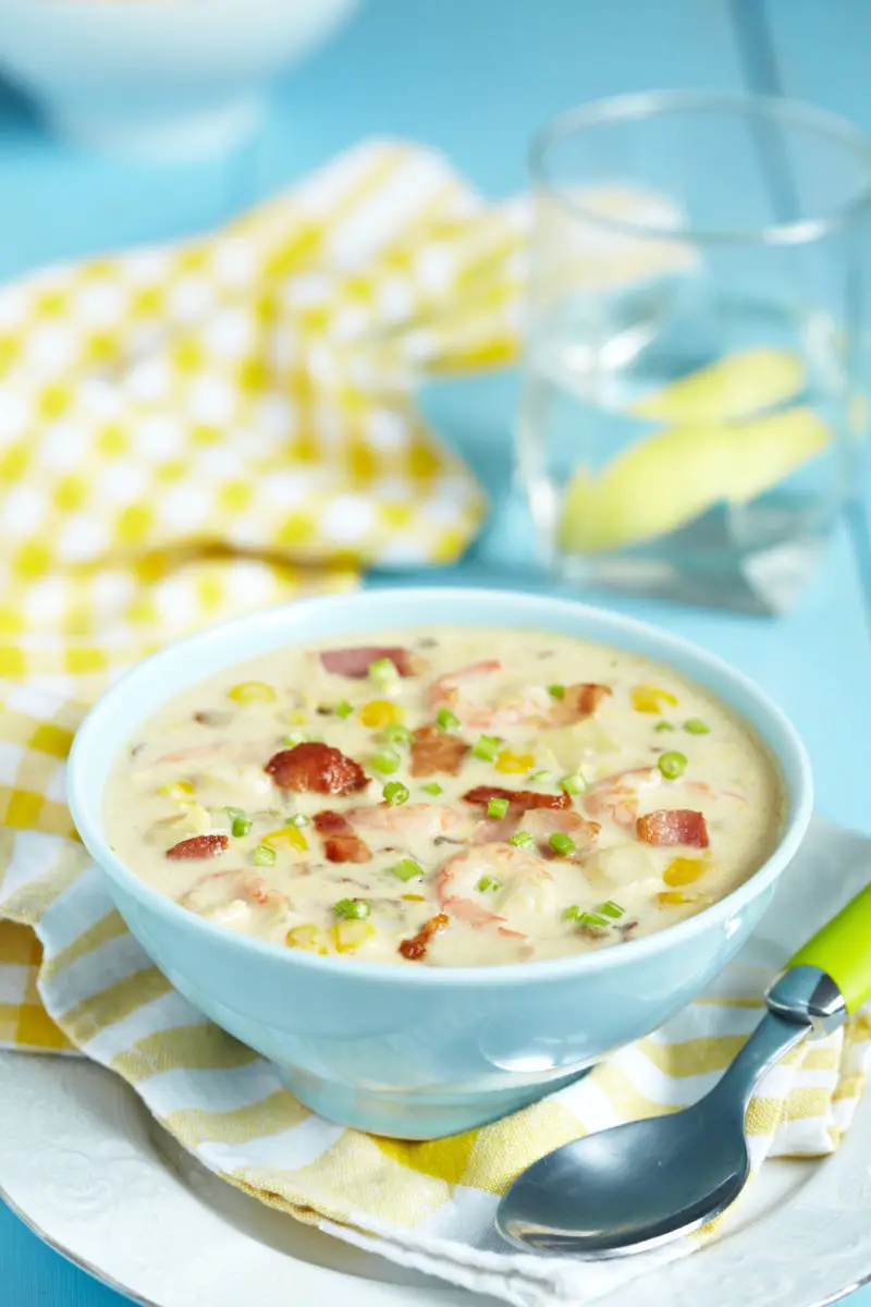 A shot of corn and shrimp chowder in a blue bowl.