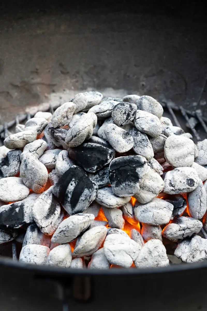 Bright red embers shining among charcoal in a grill. 