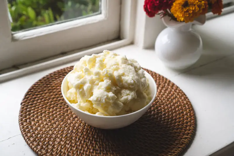 A side shot of milk-based shaved ice in a white bowl. 