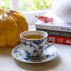 Korean plum tea in a blue tea cup next to a glass pumpkin and Korean cookbooks.