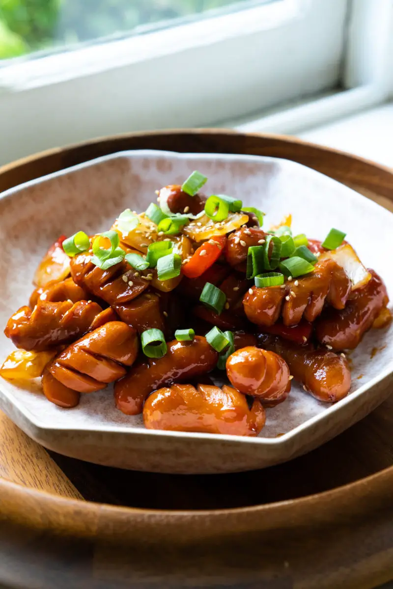 A side shot of this stir fry dish, a popular kid-friendly meal. The sausages are topped with green onions.