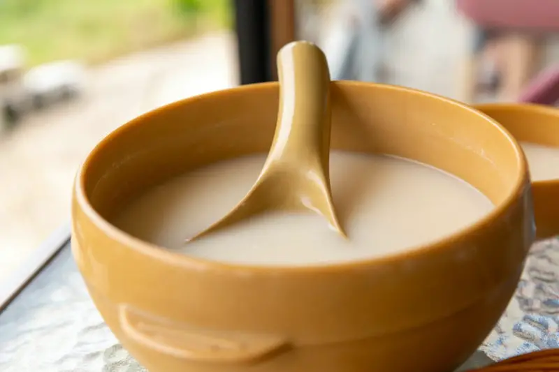 Traditional Korean alcohol (makgeolli) in a yellow bowl with a ladle. 