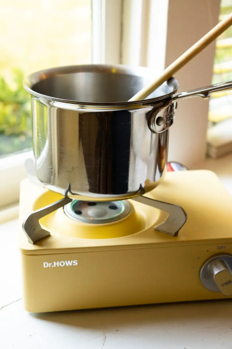 A sauce pot sitting on a yellow burner. 