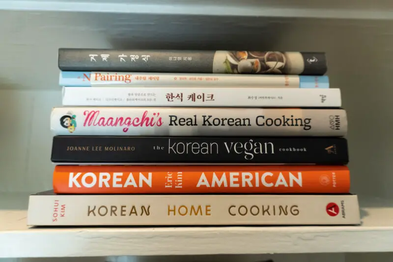 Some of my favorite Korean cookbooks I use, especially during the 2022 holiday season. These books are stacked on top of one another on a shelf.