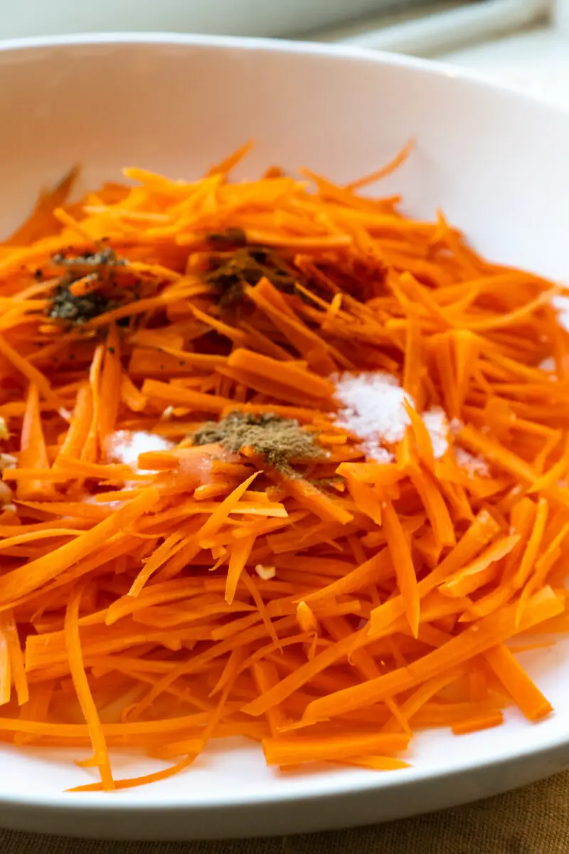 A side shot of the julienned carrots. On top of the carrots are all the spices needed for this Korean carrot salad. 