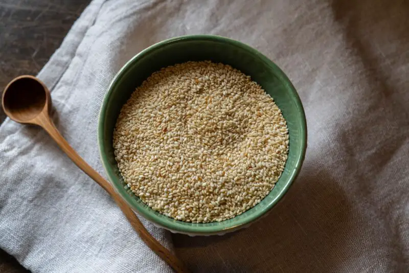 An overhead photo of cham-kkae in a bowl with a green interior. The bowl sits on a table cloth with a wooden spoon next to it.