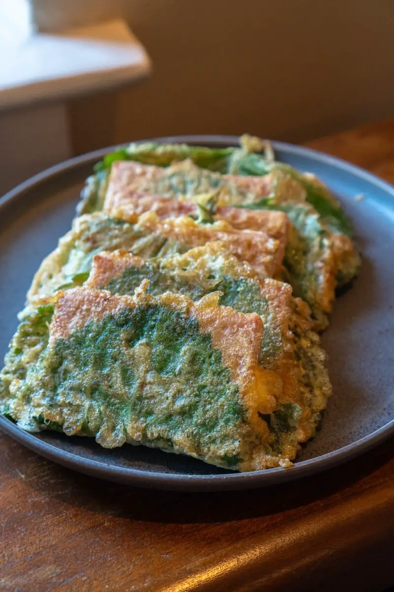 Spam perilla jeon lined up on a gray plate. The plate sits on a wooden surface.